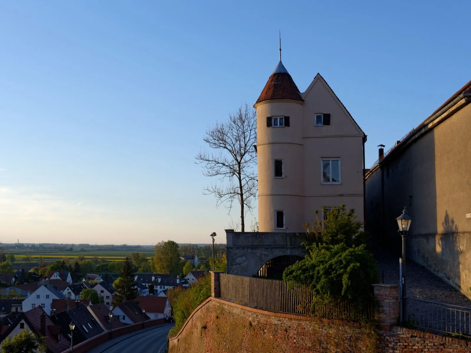 Der Rundturm an der Friedberger Stadtmauer im Abendlicht, darunter die Dächer der Unterstadt und die weite Ebene